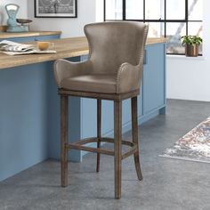 a brown leather bar stool sitting on top of a counter next to a blue wall