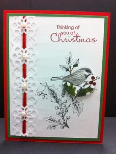 a handmade christmas card with a bird and holly leaves on it, which reads thinking of you at christmas