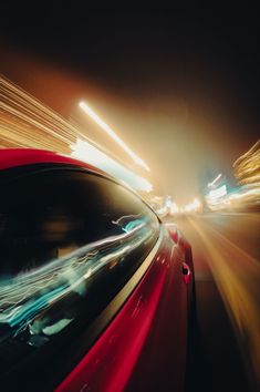 a red car driving down a city street at night with motion blurs on it