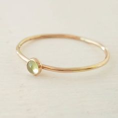 A lovely peridot gemstone has been encased in 14k gold filled and set on a 14k gold filled stacking ring. Band measures 1mm thick. Stone measures 3mm. Ring is available in all sizes. Gold Stackable Rings With Peridot Birthstone, Green Peridot Birthstone Ring, Dainty Style, Dainty Green 14k Gold Stackable Rings, Stackable Yellow Gold Peridot Jewelry, Gold Peridot Stackable Rings As Gift, Gold Stackable Peridot Rings As A Gift, Gold Stackable Rings For May Birthstone, Dainty Gold May Birthstone Ring, Gold Dainty May Birthstone Ring