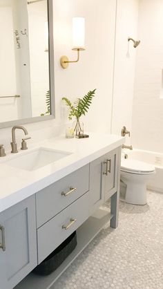 a white bathroom with two sinks and a large mirror above the sink is also a toilet