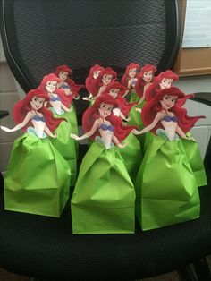 the little mermaids are sitting on top of green paper bags in an office chair