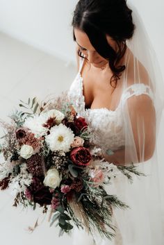 a bride holding a bouquet of flowers in her hands and looking down at the camera