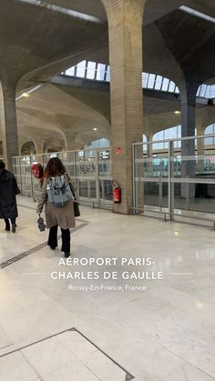 two people walking through an airport terminal with luggage on their back and the words aeroport paris charles de gauile above them