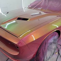 a shiny car is parked in a garage with the hood up and it's paint job done