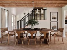 a dining room table with chairs and a vase on it in front of the stairs