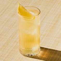 a glass filled with lemonade sitting on top of a table next to a slice of lemon