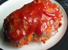 a meatloaf covered in ketchup on a white plate