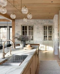 a kitchen with marble counter tops and wooden cabinets, along with hanging lights above the sink