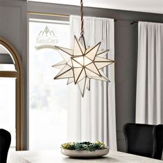 a dining room table with a white star hanging from the ceiling