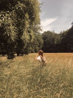 a woman walking through tall grass in the woods