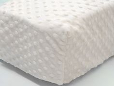 a close up view of a white bed with polka dots on the cover and pillow