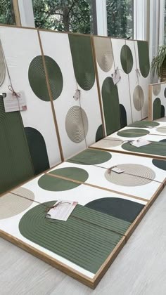 a row of green and white art work on display in a room with large windows