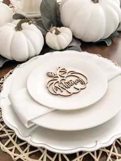 white plates and pumpkins on a wicker placemat with the word happy thanksgiving written in cursive