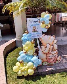 there is a winnie the pooh balloon arch in front of a sign with balloons on it