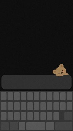 a computer keyboard with a teddy bear sitting on it's backliting keys