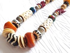 Limited Edition. Only 1 in stock.Who doesn't love an organically beautiful necklace that's light and eclectic? The Juke Joint necklace is exactly that and more. Made with repurposed beads from a vintage carved bone necklace, I took some of those elements and fashioned them into a stylishly bohemian look by adding in some great bold color elements of warm orange and yellow copal amber resin, hand-blown lampwork glass bead orbs, a batik bone focal and fun maroon carved red elephant collarbone foca Bohemian Beaded Necklace With Natural Variations, Bohemian Beaded Necklaces As Gift, Nature-inspired Necklace With Large Beads For Gifts, Red Elephant, Beach Jewelry Boho, Amber Resin, Bone Necklace, African Necklace, Carved Bone