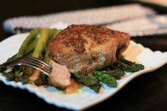 a piece of meat and broccoli on a white plate with a fork next to it