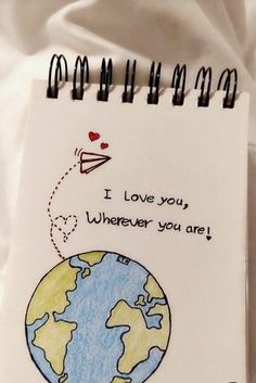 a notepad with a drawing of a plane flying over the earth and i love you wherever you are