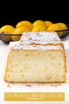 a loaf of lemon angel food cake with powdered sugar on top and fresh lemons in the background