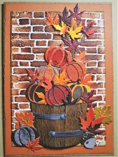 an autumn card with fall leaves and pumpkins in a bucket on a brick wall