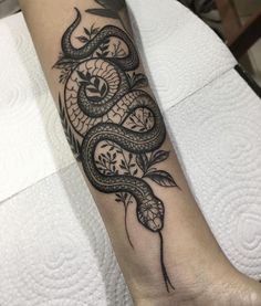 a woman's arm with a snake tattoo on it