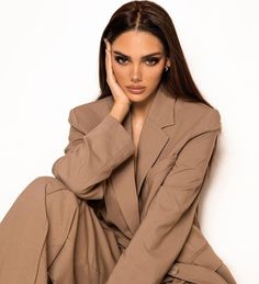 a woman sitting on the ground wearing a tan suit