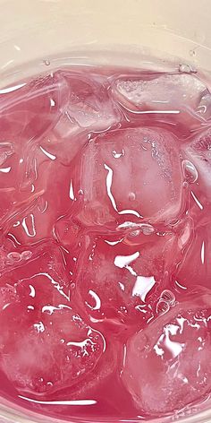 ice cubes are in a bowl with water on the bottom and pink liquid inside