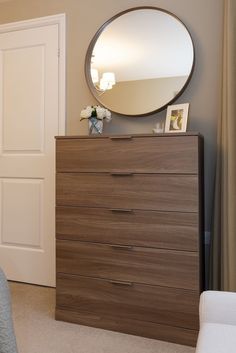 a bedroom with a dresser, mirror and chair