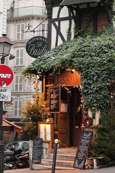 an old building with ivy growing on it's roof and signage for the restaurant