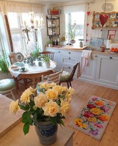 a vase filled with yellow flowers sitting on top of a wooden table in a kitchen