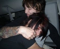 two people in the back seat of a car with tattoos on their arms and shoulder