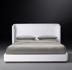 a white bed with two pillows sitting on it's headboard and foot board