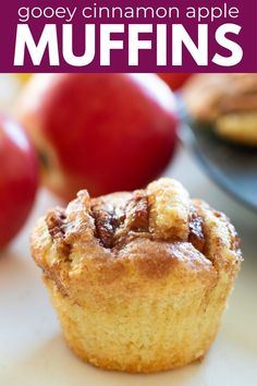 an apple muffin is sitting on a table with apples in the background and text overlay that says gooey cinnamon apple muffins