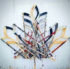 a bunch of skis sitting on top of a wooden pole in front of a white wall