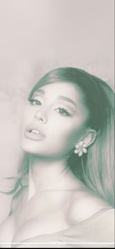 a woman with long hair and earrings posing for a photo in front of a white frame