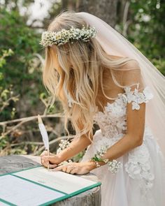 a woman in a wedding dress writing on a piece of paper