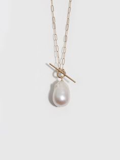 This necklace brings together the contrasting elements of delicate open oval links of 14Kt yellow gold chain, a charming toggle bar front closure, and a dramatic baroque teardrop pearl pendant to create a luxe piece with unique details. 14Kt Yellow Gold Long Link Chain 14x17mm Teardrop Baroque Pearl Length: 16" Made in L.A. Globally Sourced Materials Each pearl is unique, no two are exactly the same. Timeless Baroque Pearl Jewelry, Elegant Toggle Necklace With Cable Chain For Formal Occasions, Elegant Toggle Necklace With Cable Chain For Formal Events, Elegant Pendant Toggle Necklace, Timeless Pear-shaped Gold Necklace, Gold Toggle Necklace With Pearl Charm, Elegant Teardrop Cable Chain Necklaces, Elegant Teardrop Cable Chain Necklace, Elegant Gold Toggle Necklace With Pearl Charm