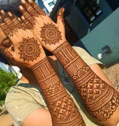 two people with henna tattoos on their hands and arms, one is holding the other hand