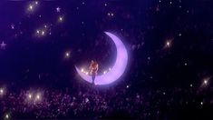 a man standing on top of a moon in the middle of a stage filled with people