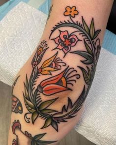 a woman's foot with tattoos on it and flowers in the middle of her leg