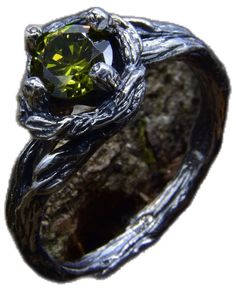 a silver ring with a green stone in it's center, on top of a rock