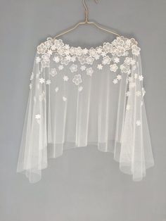 a white wedding veil hanging on a hanger with flowers and leaves attached to it