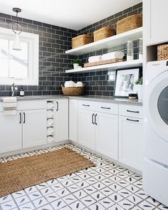 a laundry room with white cabinets and tile flooring, including a washer and dryer