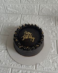 a birthday cake with black frosting and gold sprinkles