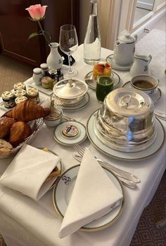 the table is set for two people to enjoy their afternoon tea and desserts, including croissants