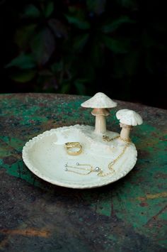 two mushrooms sitting on top of a plate with gold chains around their ankles and rings in the middle