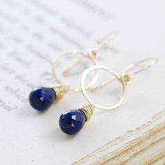 Beautiful navy blue lapis lazuli briolettes swing below hoops I've hand formed out of 14k gold filled wire in these striking gemstone earrings. This lapis is really outstanding, with occasional tiny natural flecks of pyrite that highlight the gold. Total length is approximately 1 5/9 inches (4.2 cm), and the circles are a little under 1/2 inch (1.2 cm) across. The lapis briolettes are about 10 mm x 6 mm. Earrings are available in 14k gold fill (pictured) or sterling silver. Please select your op Round Lapis Lazuli Gemstone Earrings, Pierced Lapis Lazuli Round Jewelry, Handmade Lapis Lazuli Jewelry For Everyday, Minimalist 14k Gold Filled Blue Earrings, Minimalist Blue 14k Gold Filled Earrings, Minimalist Round Lapis Lazuli Jewelry, Blue Lapis Lazuli, Blue Lapis, September Birthstone