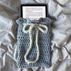 an open book laying on top of a bed next to a crocheted bag