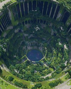 an aerial view of a circular building surrounded by trees and bushes in the middle of a park